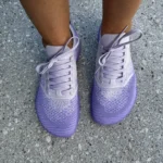 Pair of purple barefoot sneakers on concrete ground.