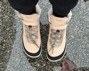Beige waterproof barefoot boots standing in a shallow puddle.