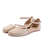Beige ballet flats with ankle strap, studio background